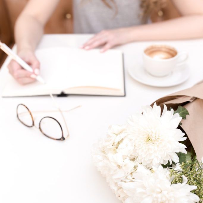 Girl writing in pad, glasses and bunch of flowers Girl writing in pad, glasses and bunch of flowers