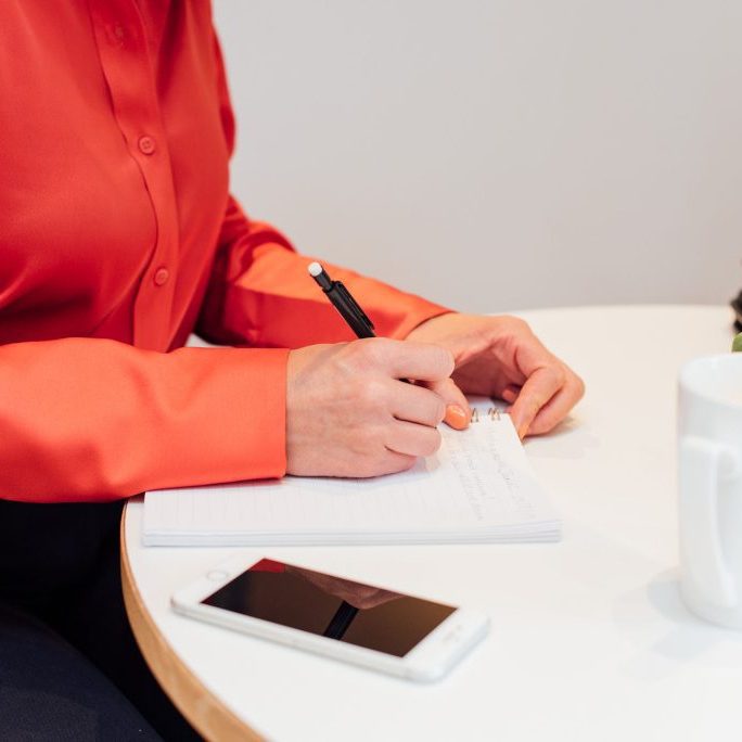 Kellie-Simpson-VA-Virtual-Assistant-Legal-Support-Web-225 Lady sat at table with a notebook and phone planning for an event.
